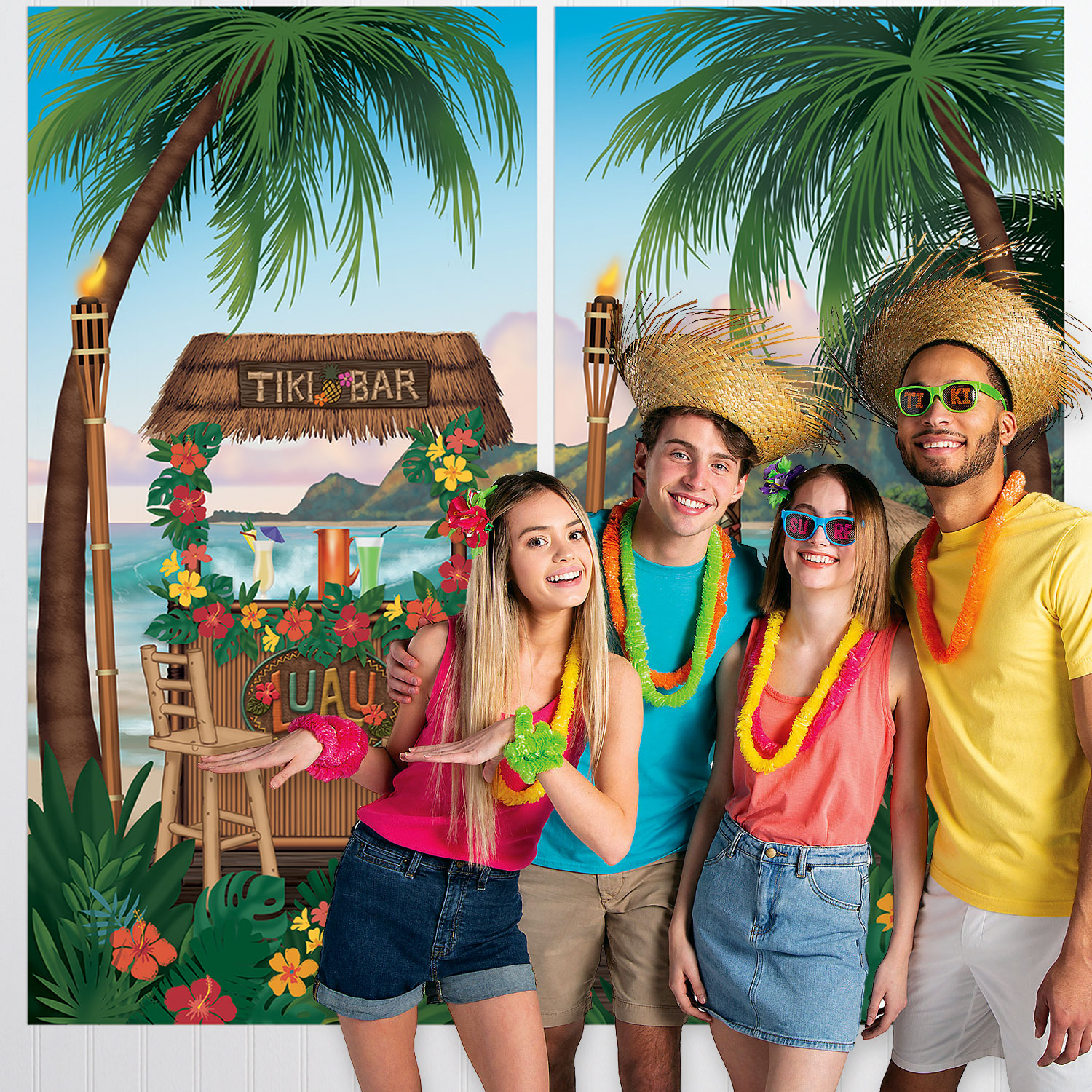 Four people smiling at a tropical-themed party, with palm trees, a tiki bar, and colorful decorations in the background.