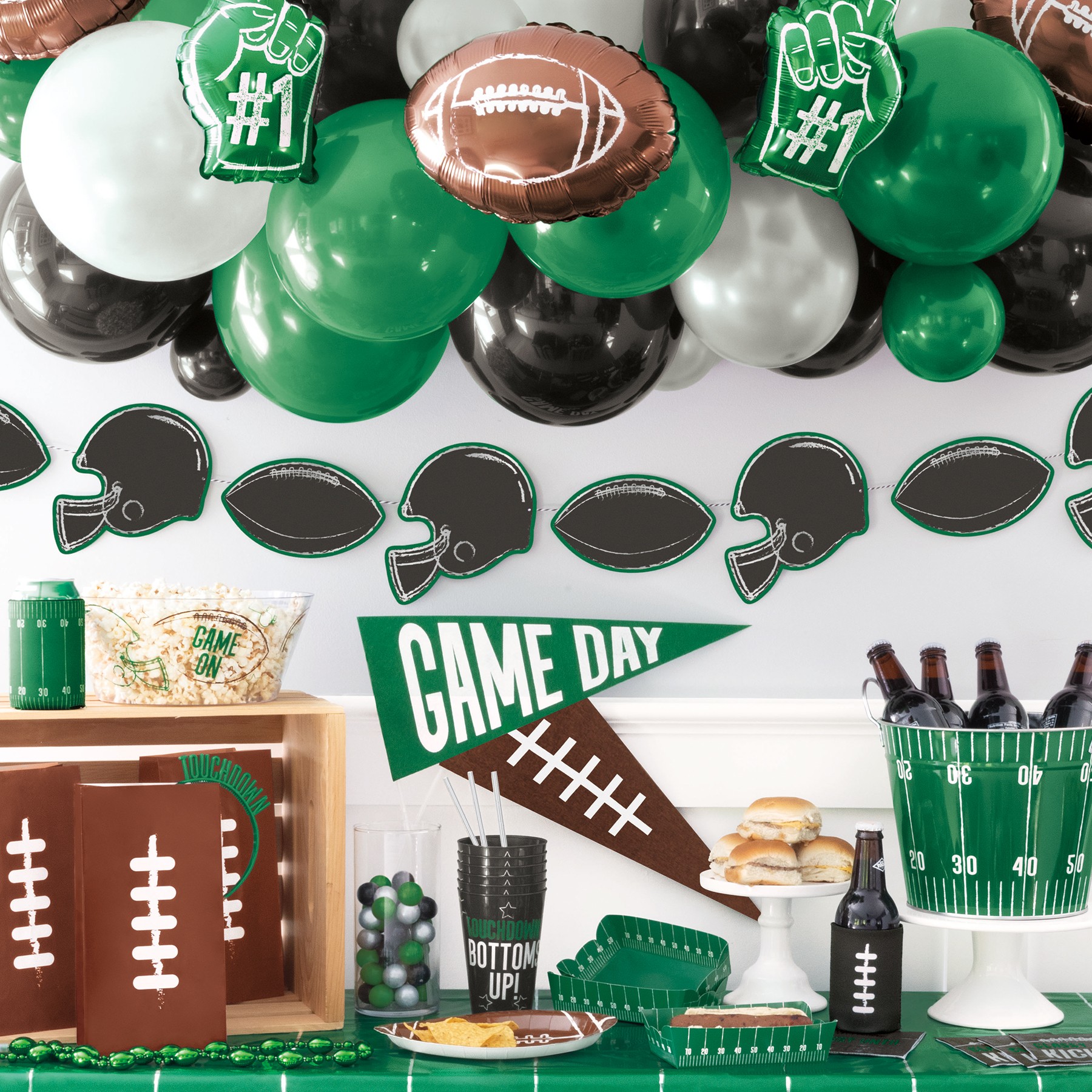 Football-themed decorations with balloons, helmets, and a cake, celebrating game day with snacks and party supplies.