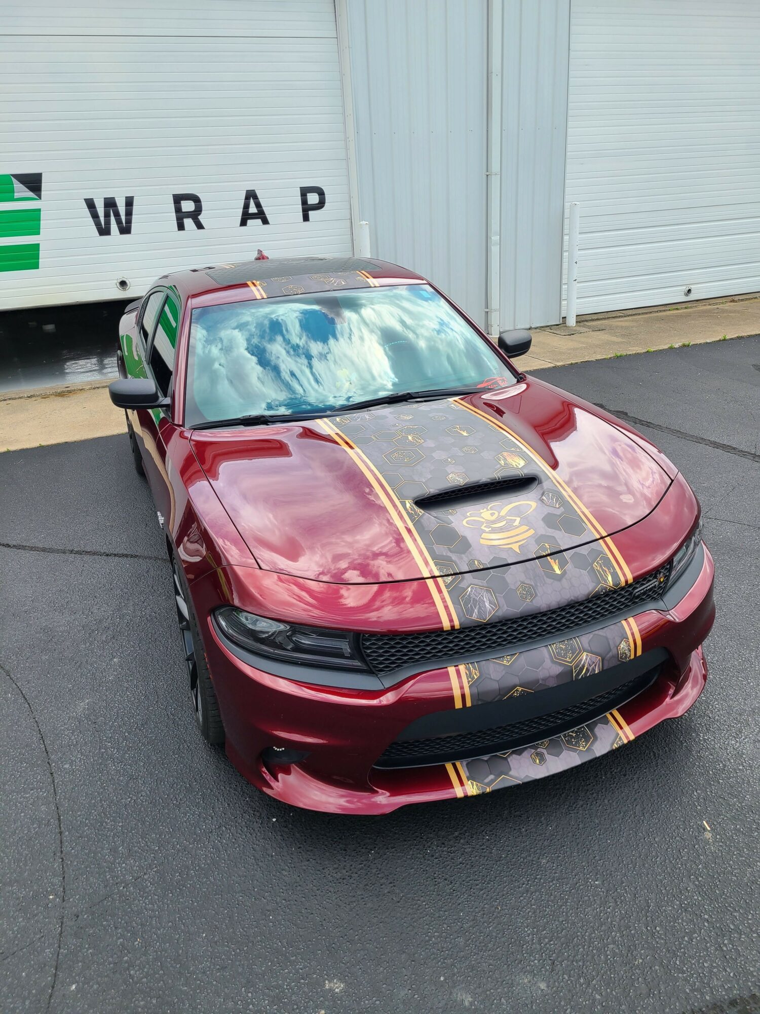 Red sports bag with black straps on asphalt, near a white wall with a sign reading 'W R A P'.