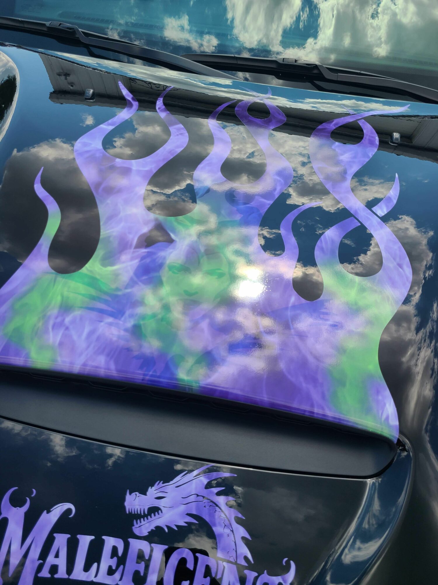 Close-up of a vehicle with purple and black decorative designs, including a dragon and swirling patterns, on the hood.