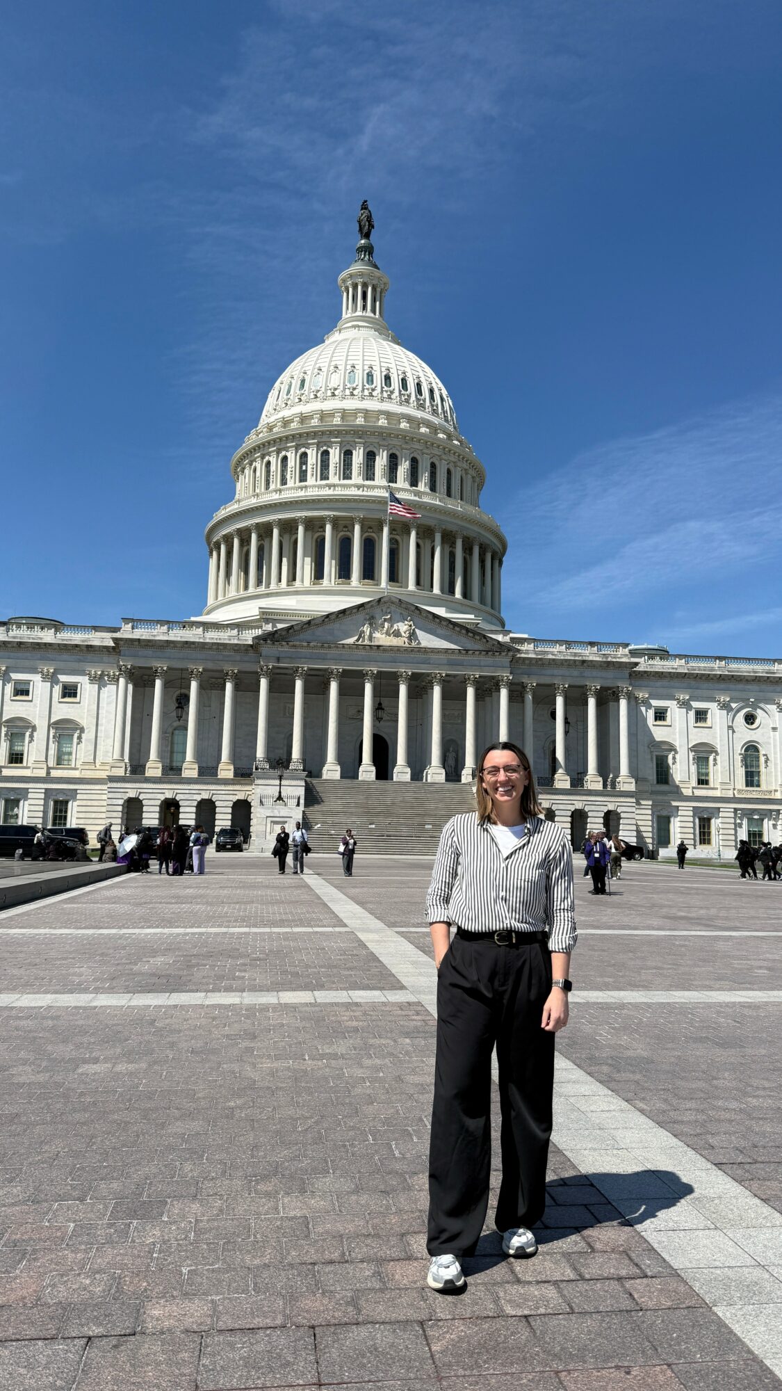 Woman standing in front of the U.S. Capitol building on a sunny day.
