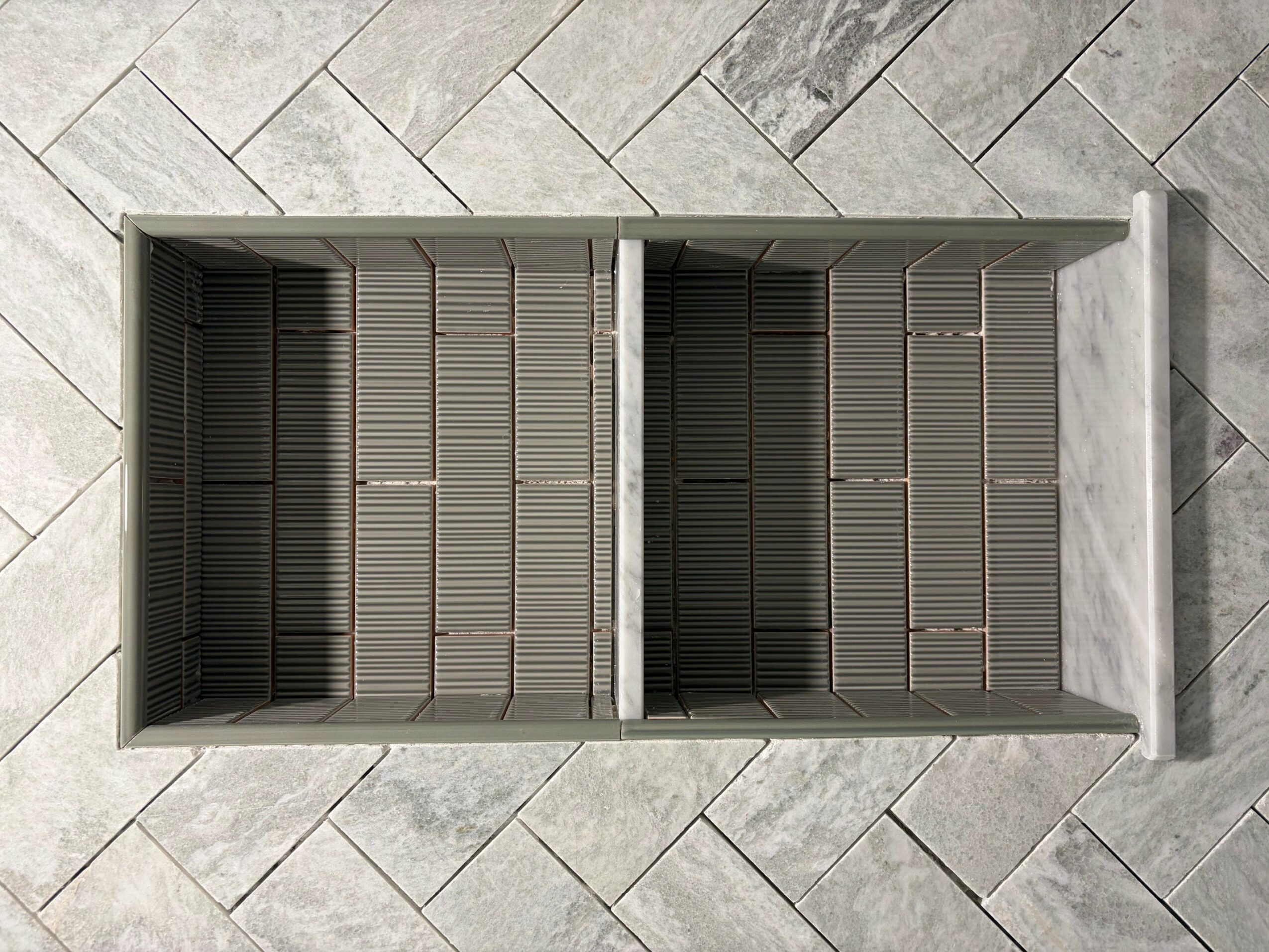 Open shoe storage with multiple compartments, on a tiled floor, viewed from above.