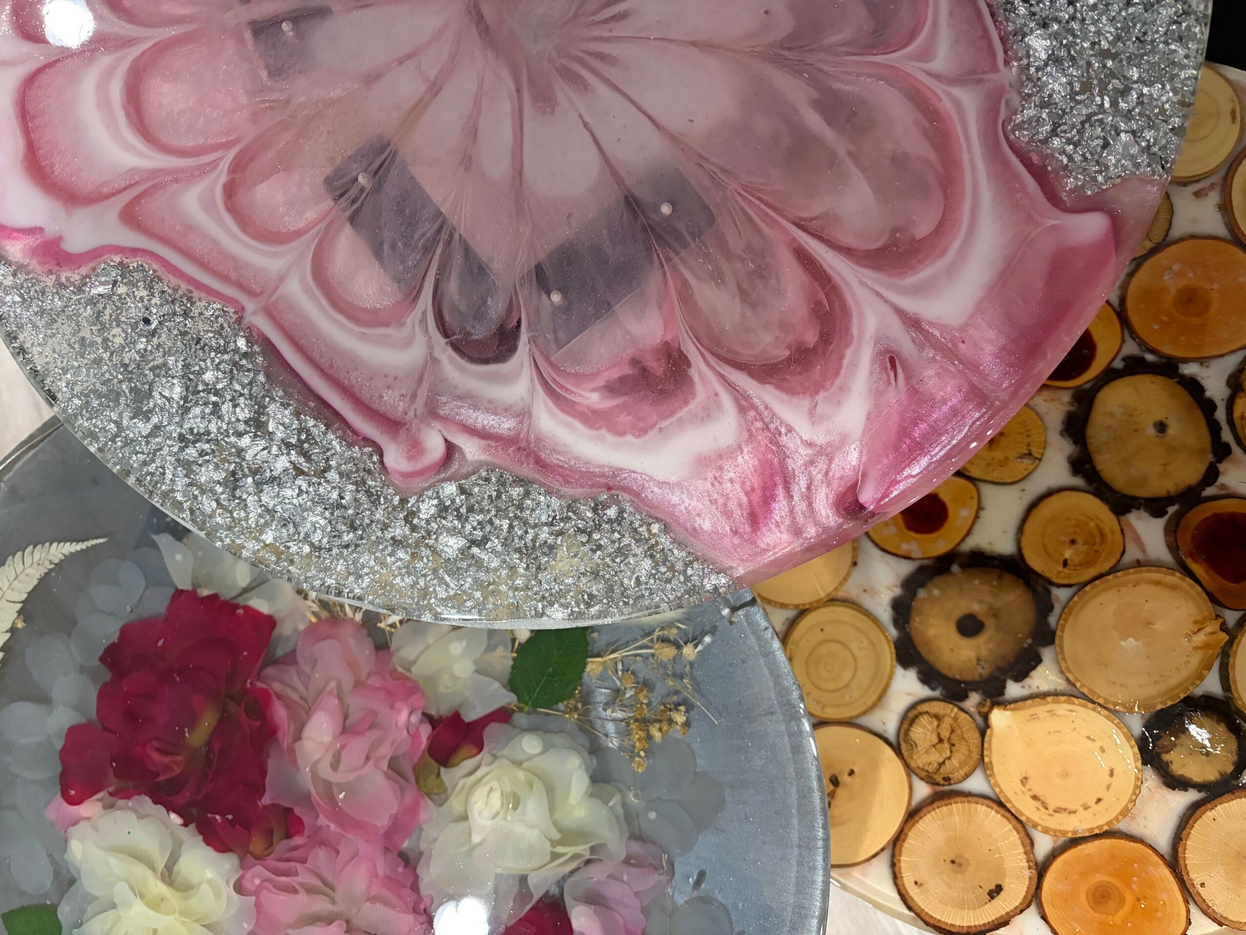 Close-up of a pink and white marbled cake with a glittery silver border, surrounded by sliced fruit or wood slices.
