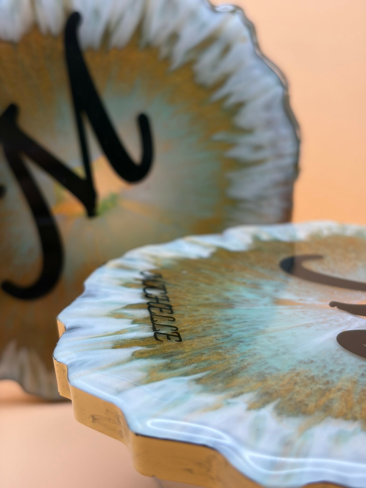 Close-up of two decorative plates with abstract designs, one in the foreground and one in the background, against a plain wall.