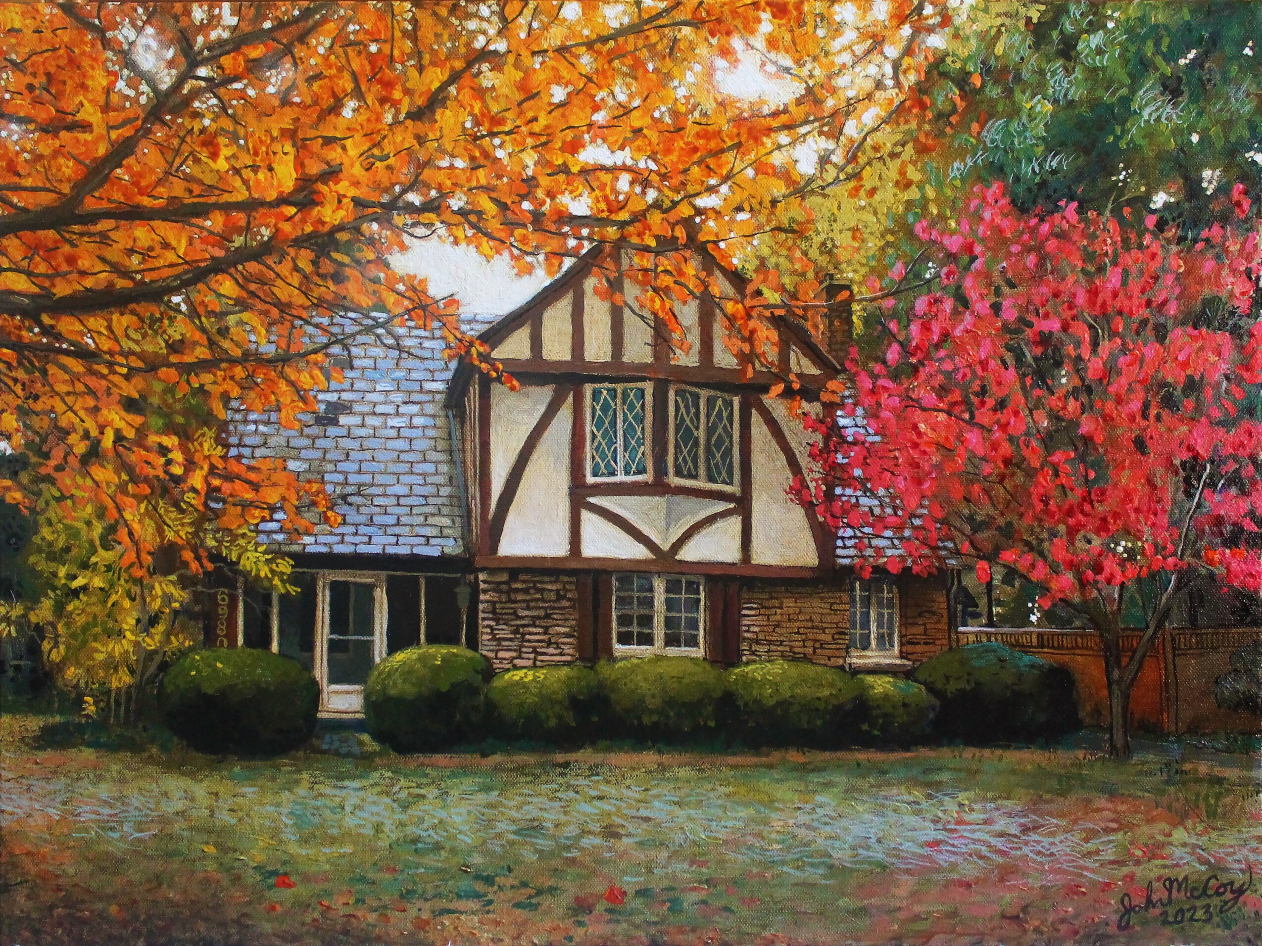 A house with a Tudor-style facade surrounded by colorful autumn trees and a grassy lawn.