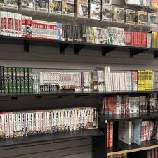 Bookshelves filled with manga and comic books in a store, arranged on black shelves.