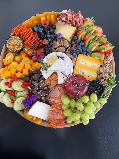 Colorful assortment of fruits, cheeses, chocolates, and snacks arranged on a platter.