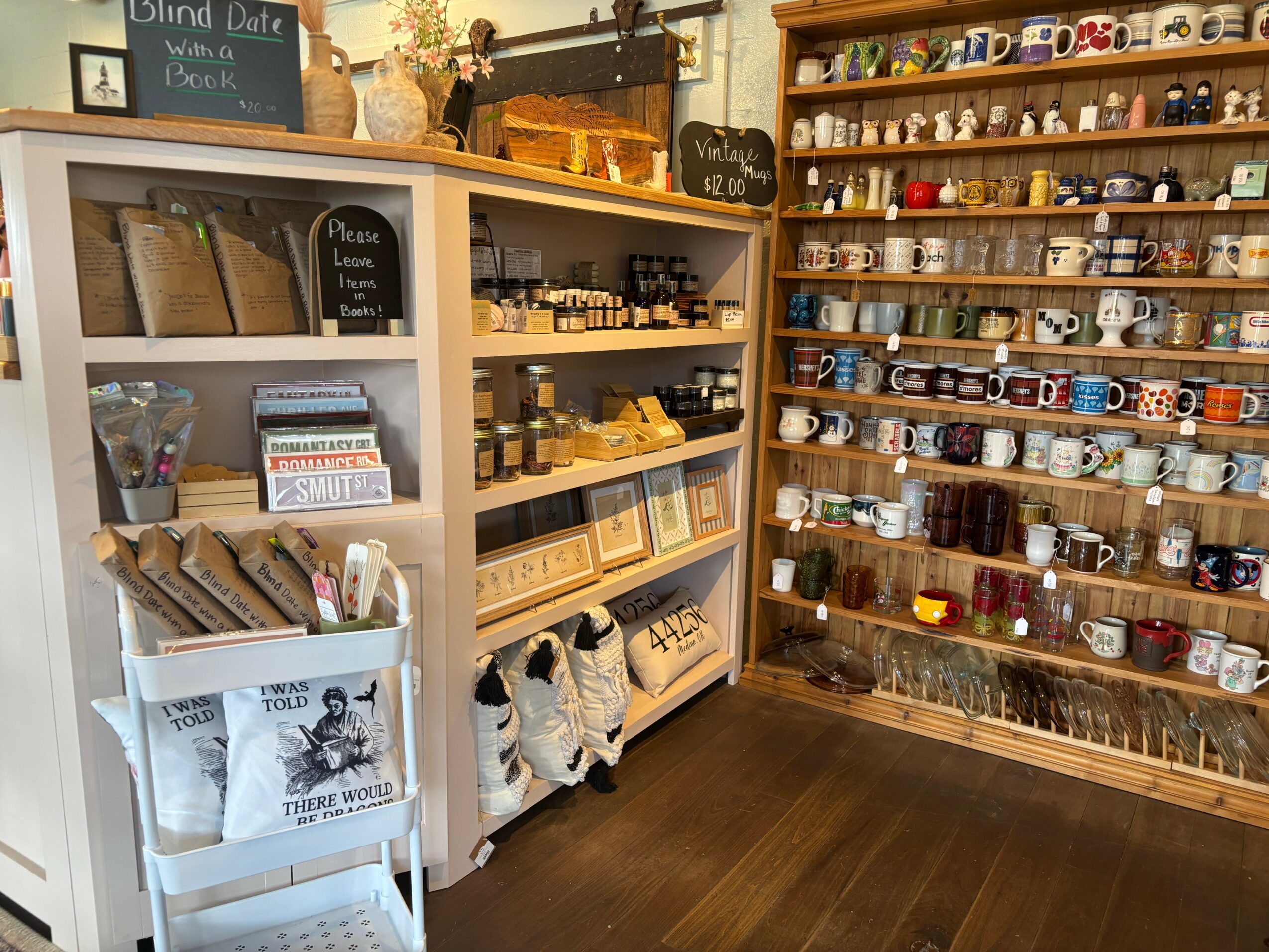 Display shelves with various jars, mugs, and decorative items in a store, wooden flooring, and organized product arrangement.