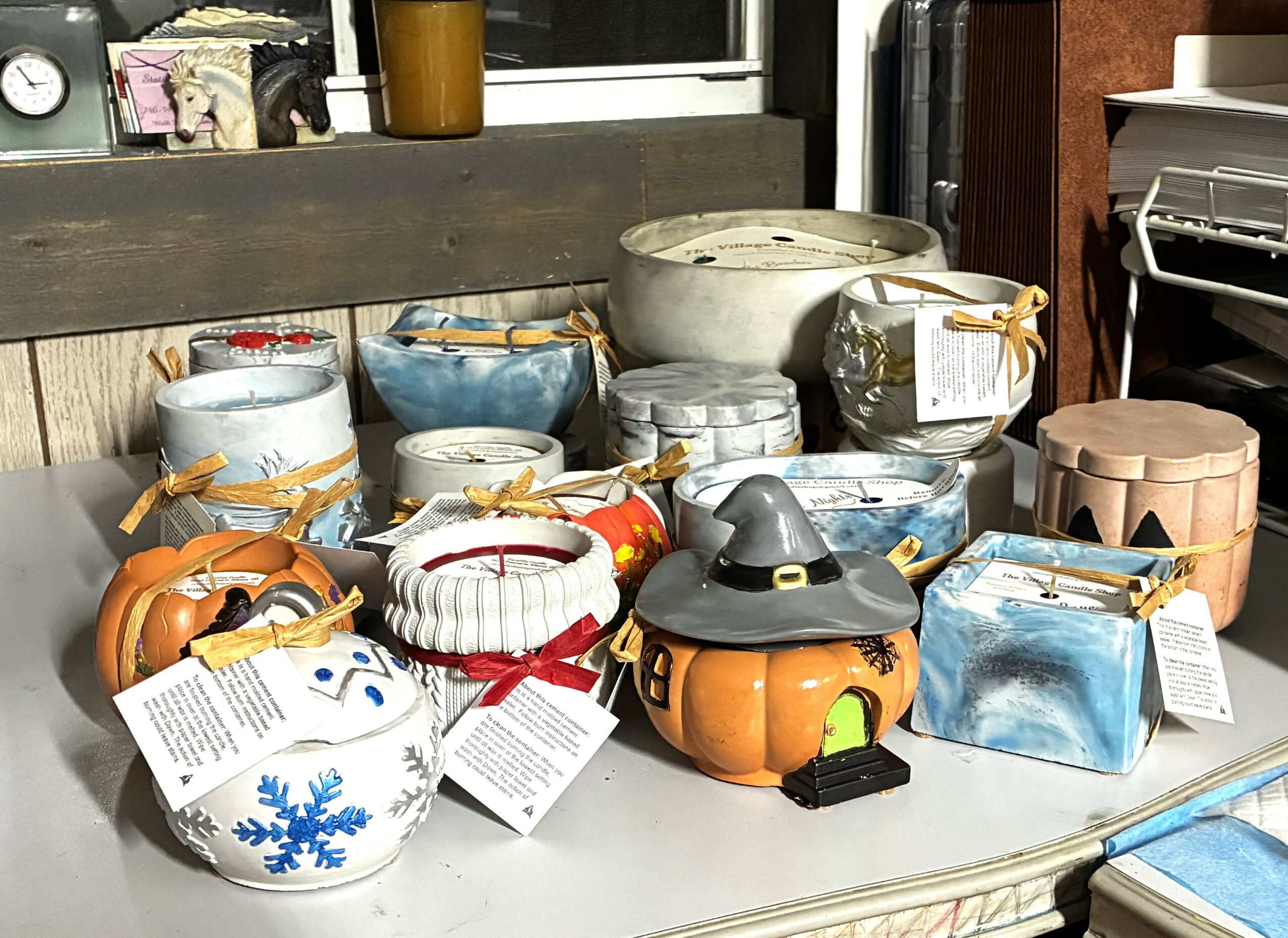 Collection of ceramic and decorative pumpkin-shaped containers with ribbons, a witch hat, and wrapped gifts on a table.
