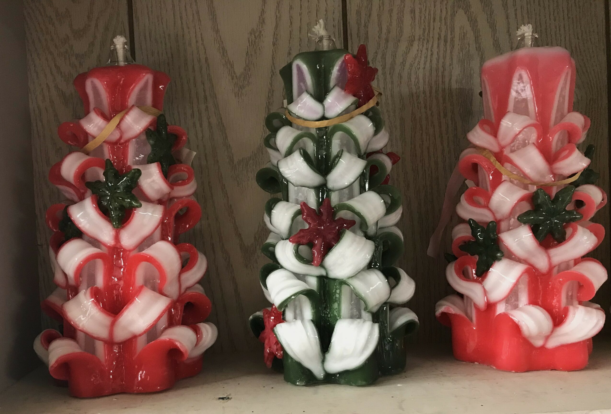 Three decorative candles with ribbon and star ornaments, arranged on a wooden surface.
