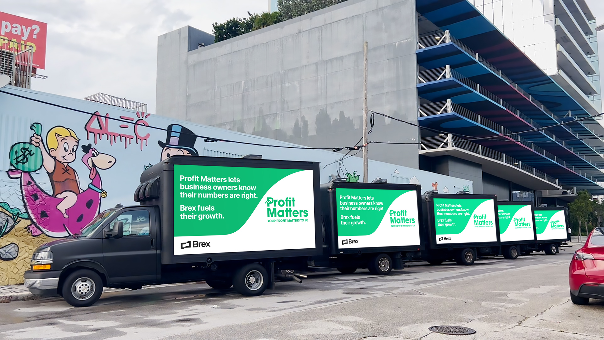Multiple digital screens on a truck display messages about mental health awareness, parked in front of a mural and modern building.