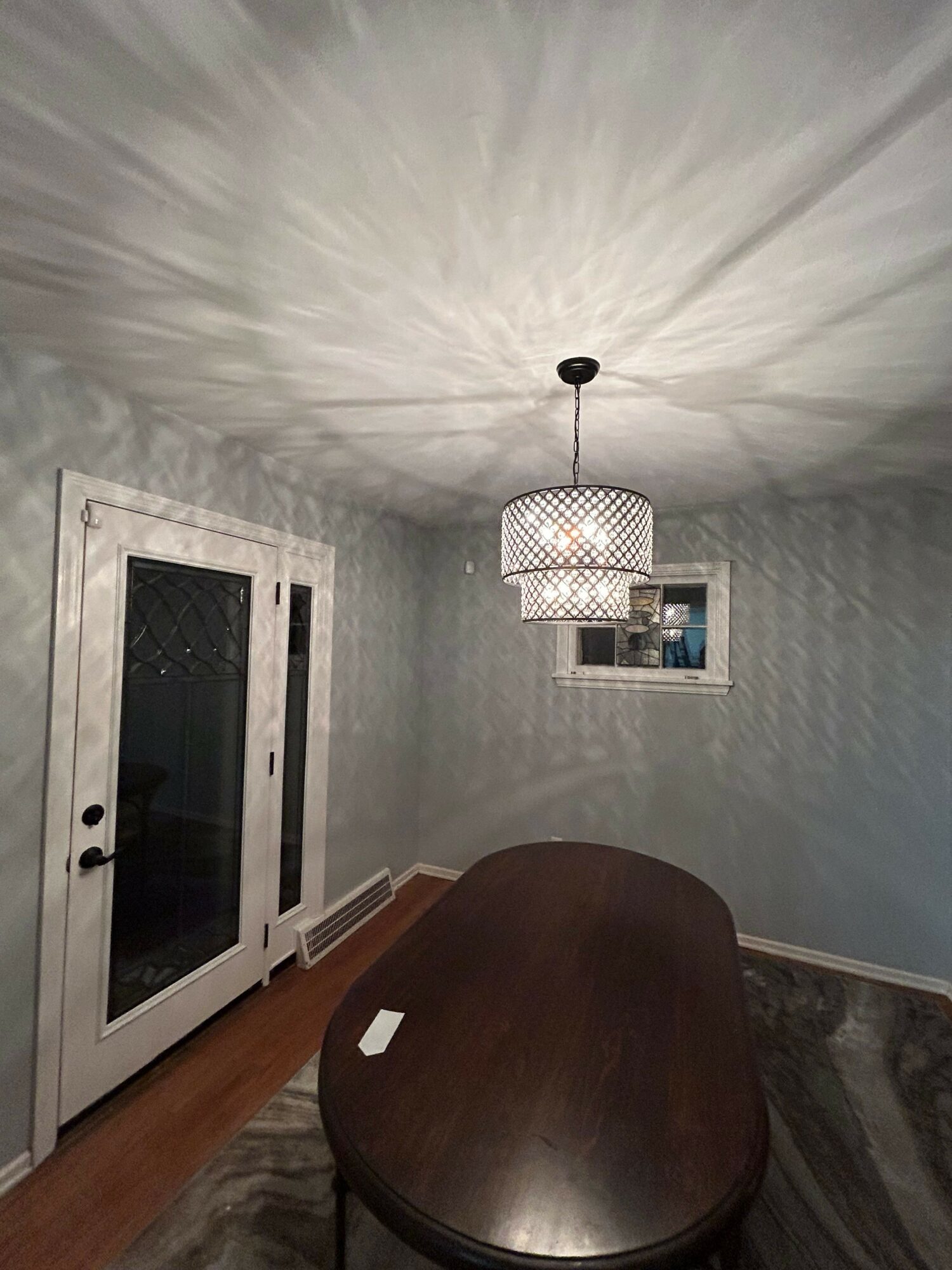 Room with a window, a hanging light fixture, and a wooden table, viewed from the floor looking upward.