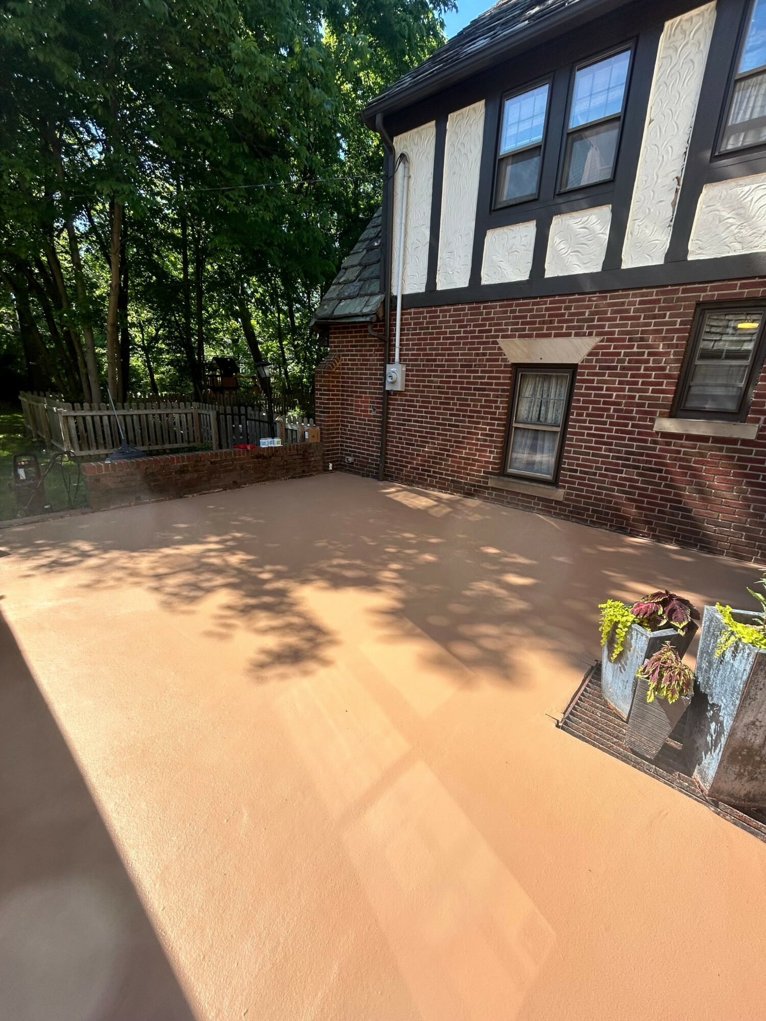View of a brick building with windows and a small outdoor area with trees and shadows, taken from an angle.
