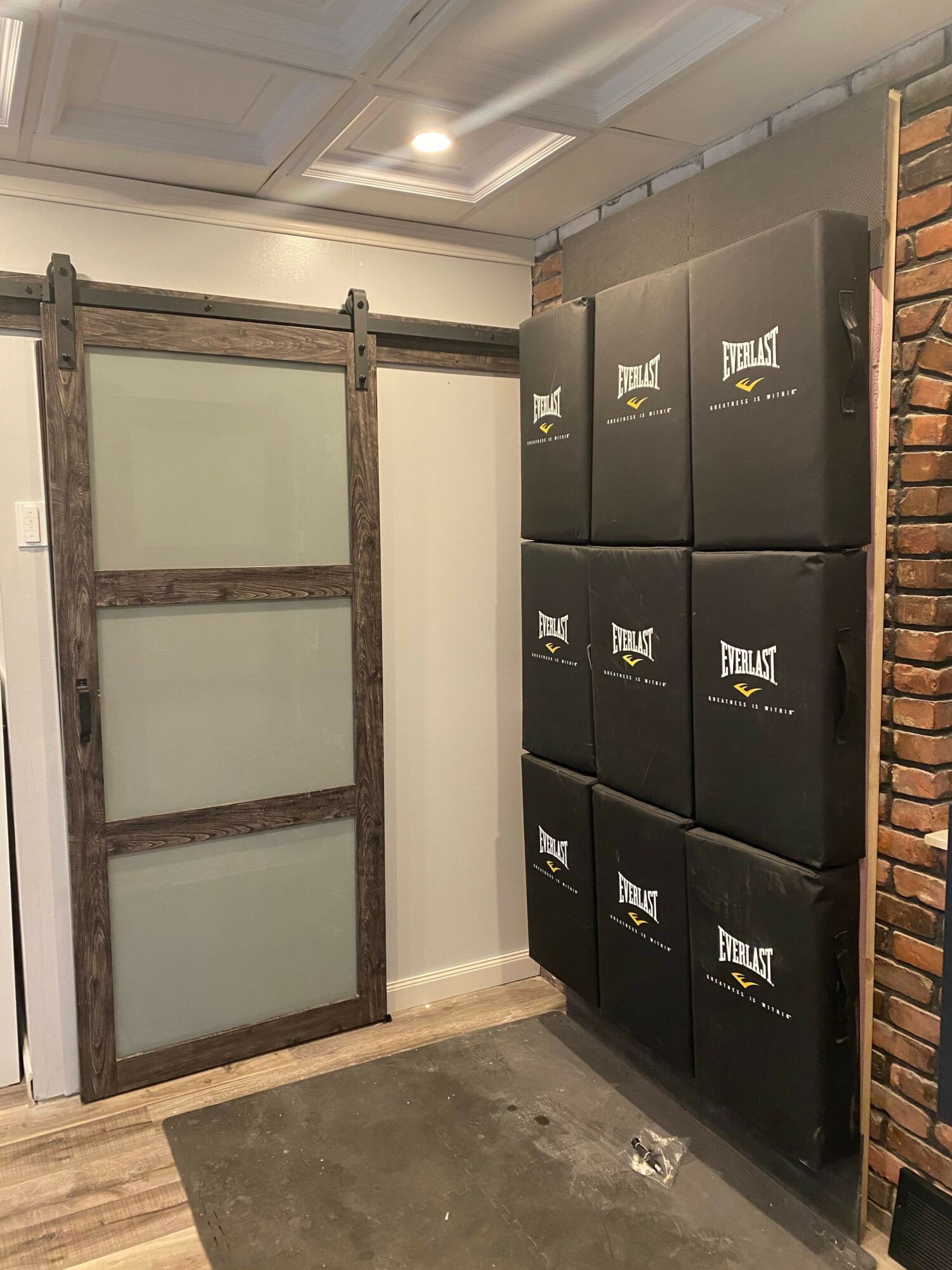 Black storage boxes stacked on a shelf, a wooden frame with frosted glass panels, and a brick wall in the background.