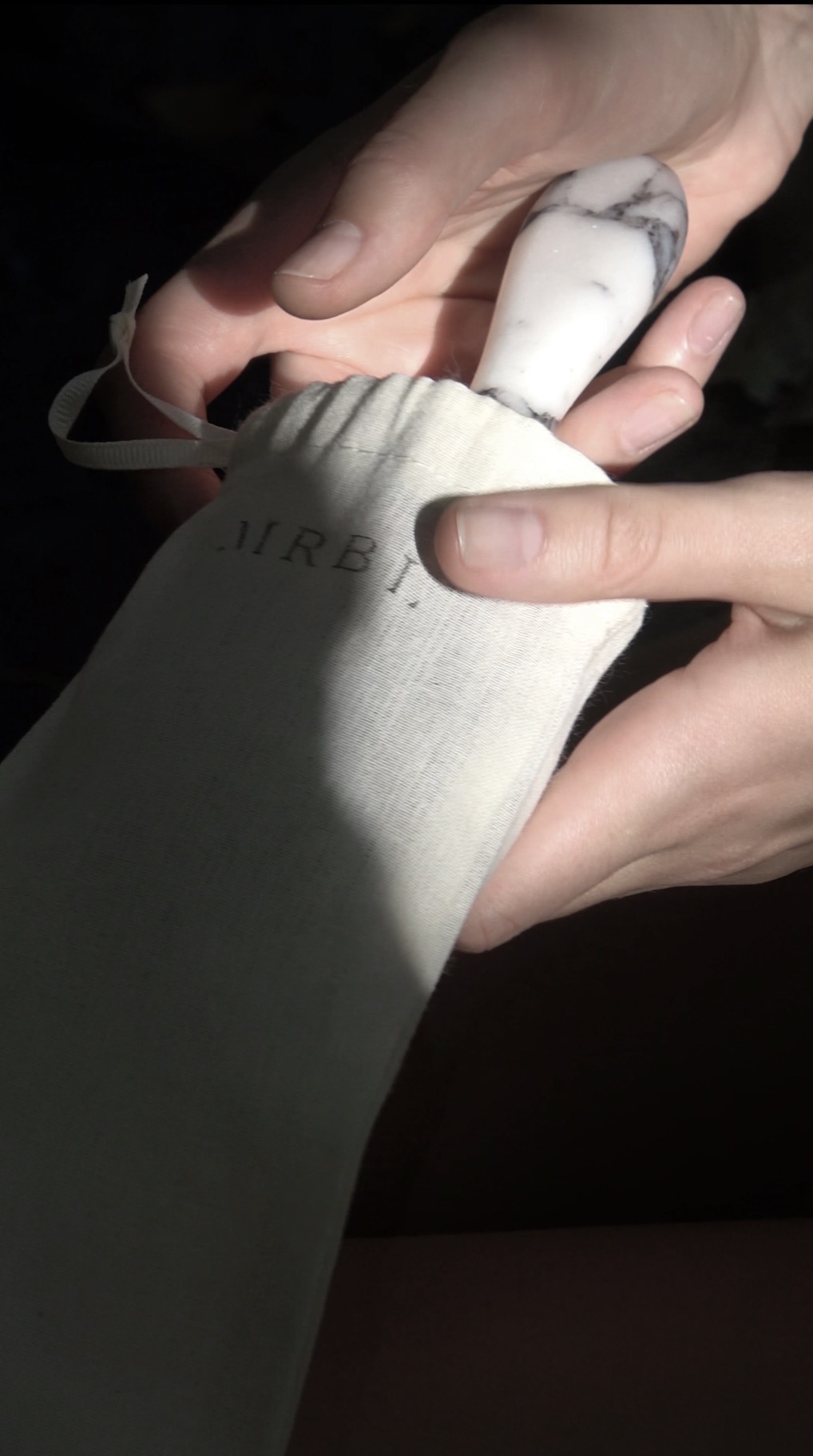 Person holding a white marble-patterned object with a shadowed background.