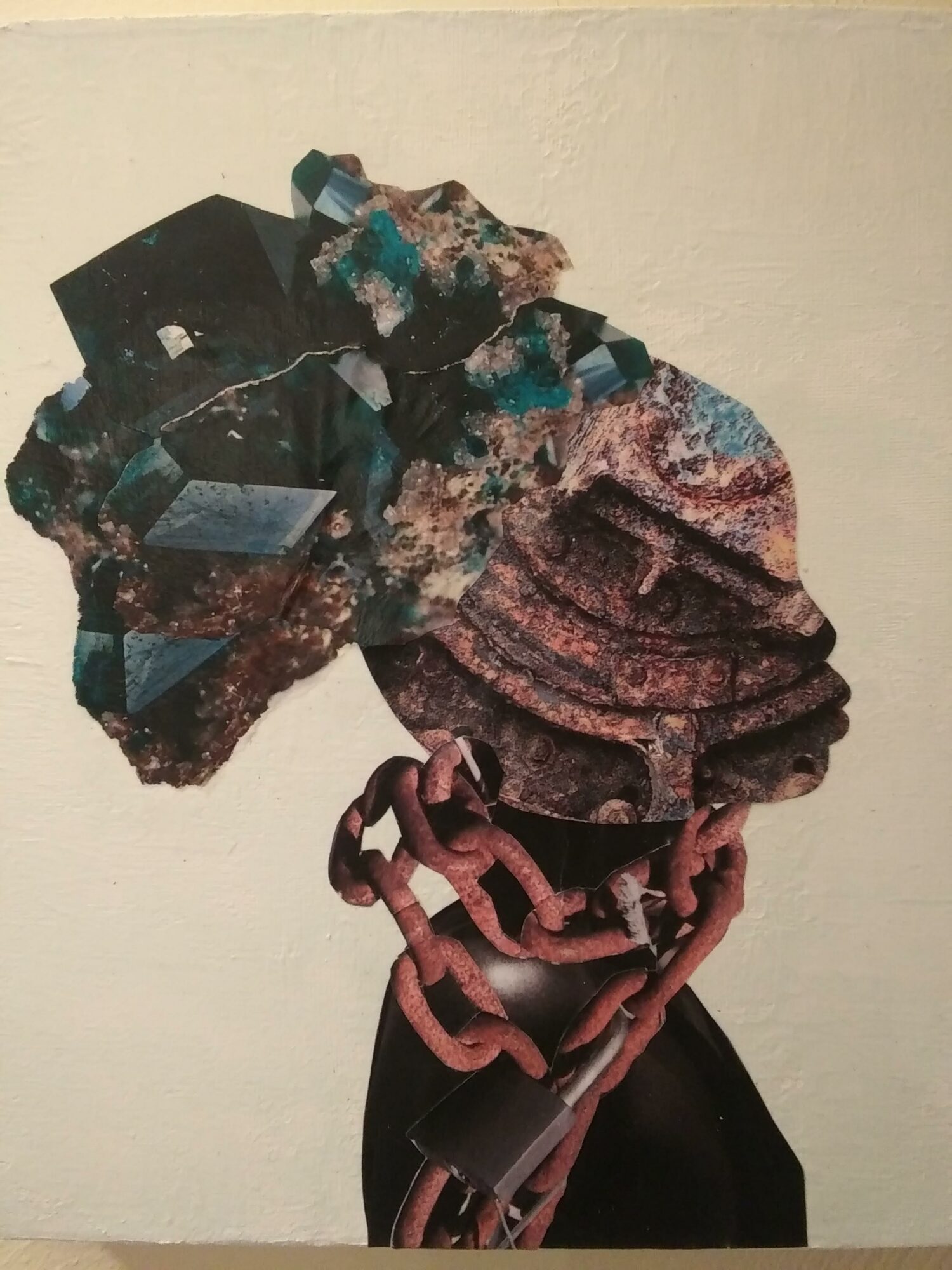 A sculpture of a face with chains and geometric shapes, mounted on a wall, with a black background on the right side.