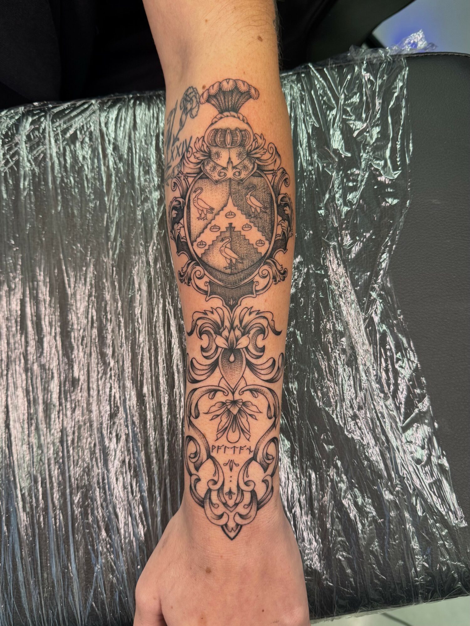 Tattoo of a clock with floral and ornamental designs on a person's forearm.