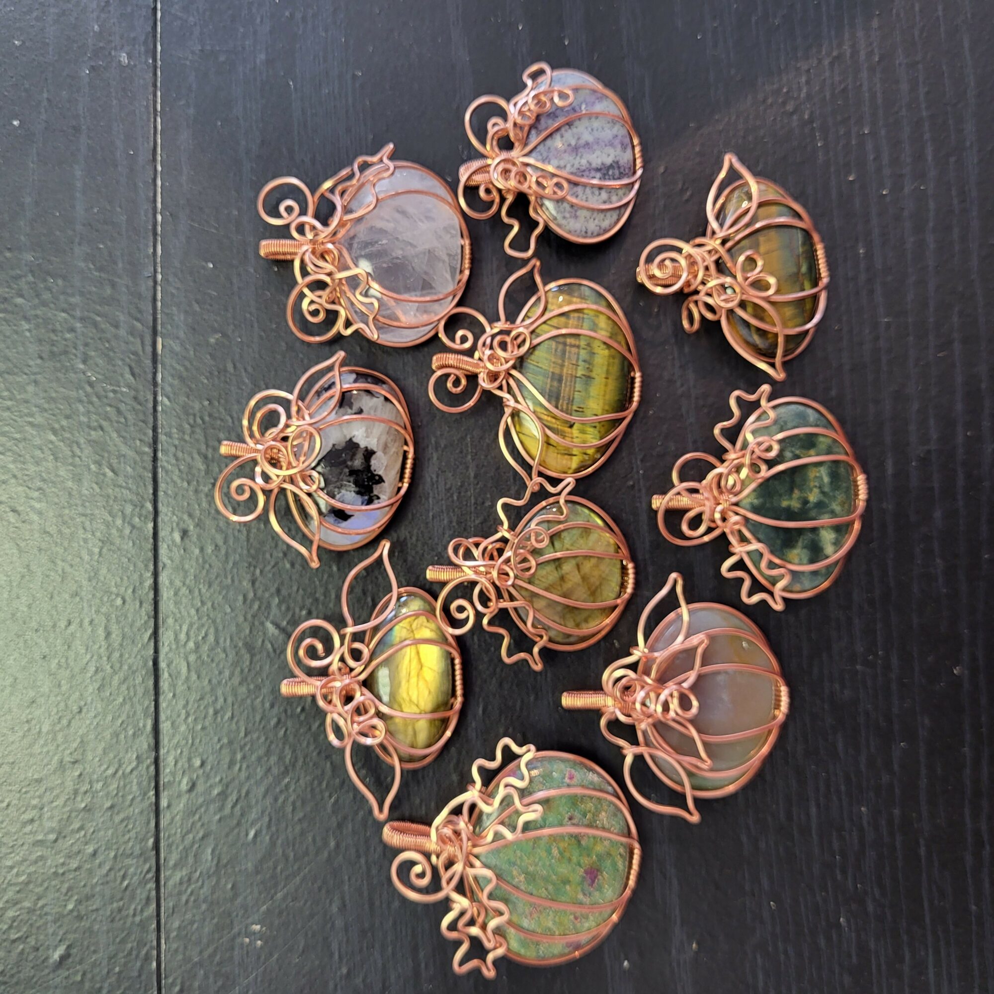 Collection of wire-wrapped glass orbs with colorful patterns, arranged on a dark surface.