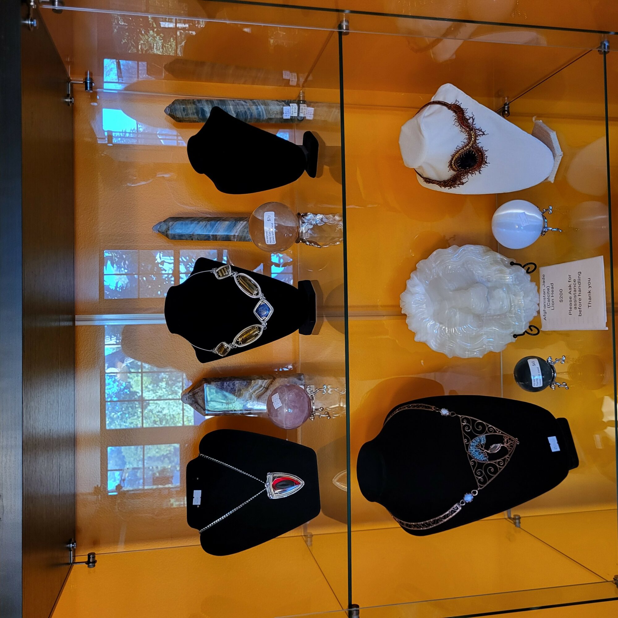Display case with black and white fashion accessories, jewelry, and decorative items against an orange background.