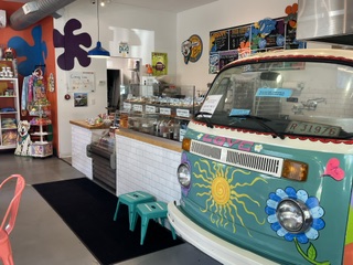 Colorful interior of a shop with a decorated vehicle, shelves with products, and playful wall decorations.