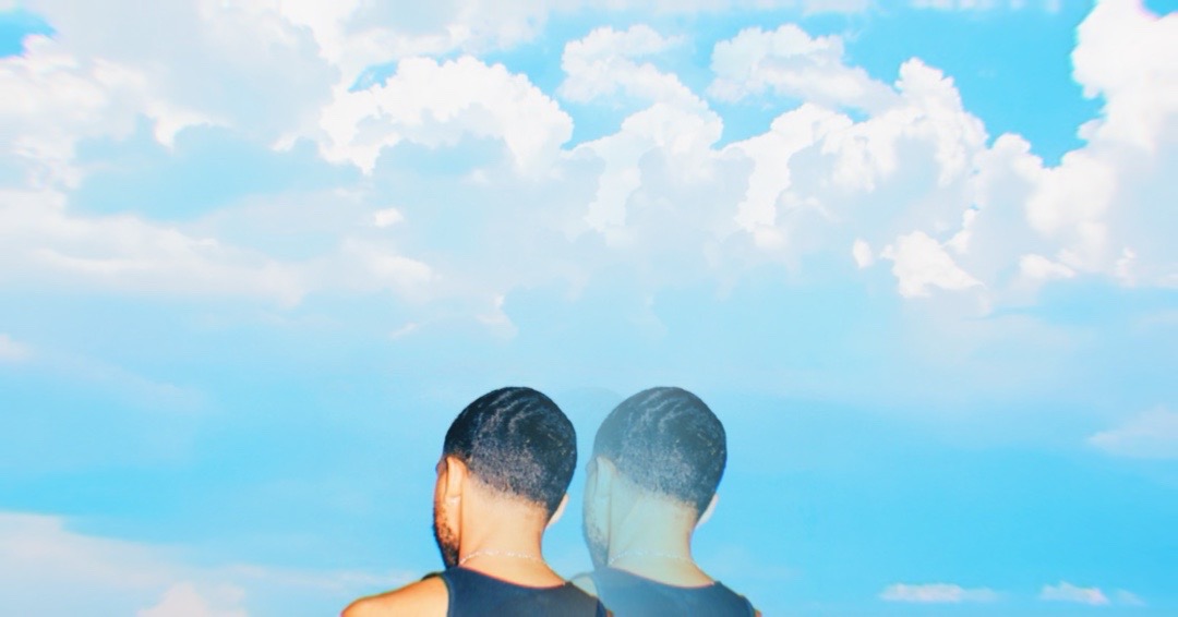 Two people with short dark hair facing away, against a bright blue sky with clouds