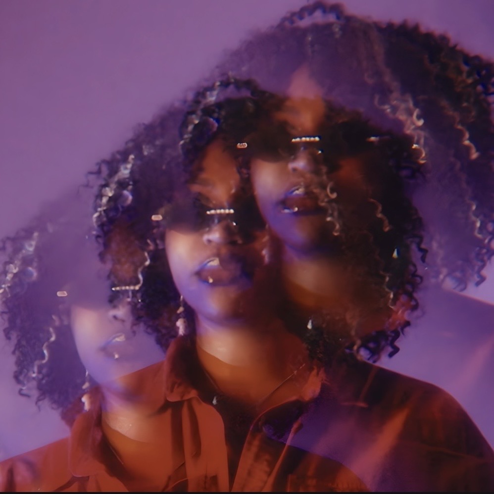 Multiple overlapping images of a woman with curly hair wearing sunglasses and a red shirt, with purple lighting.