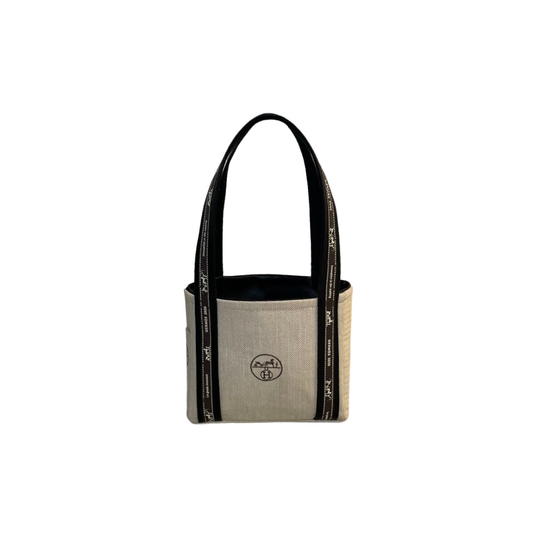 Small beige tote bag with black handles and logo, isolated on white background.