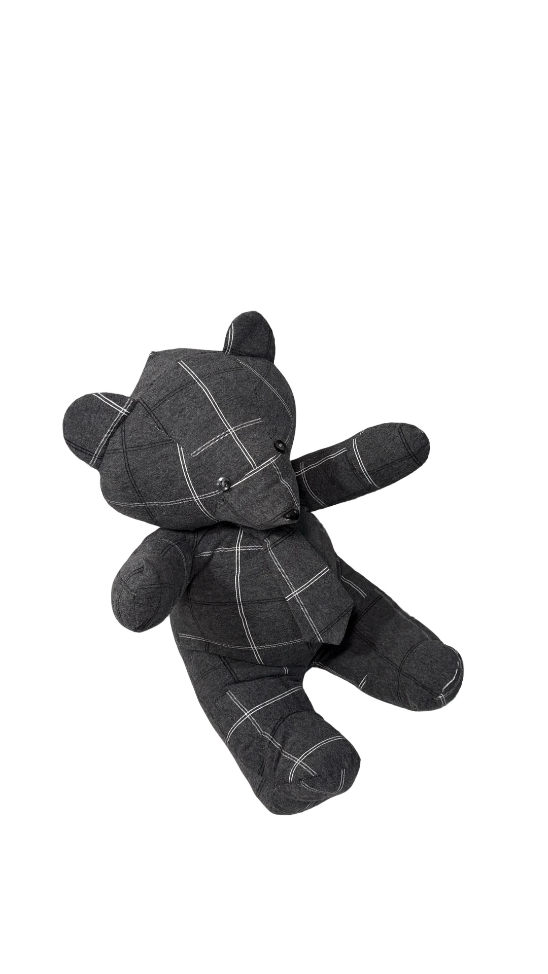 Black plush teddy bear with a checkered pattern, sitting upright on a white background.