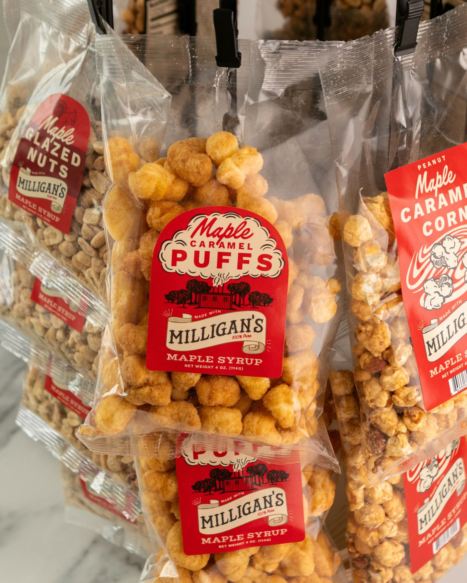 Clear plastic bags of caramel popcorn with red and white labels, displayed on a store shelf.