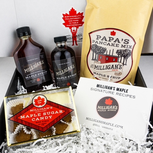 Maple syrup bottles, pancake mix, candy, and recipe cards in a gift box with shredded paper.