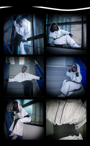 Six people in white outfits sitting and standing near large windows, some looking at the camera, in a modern building.