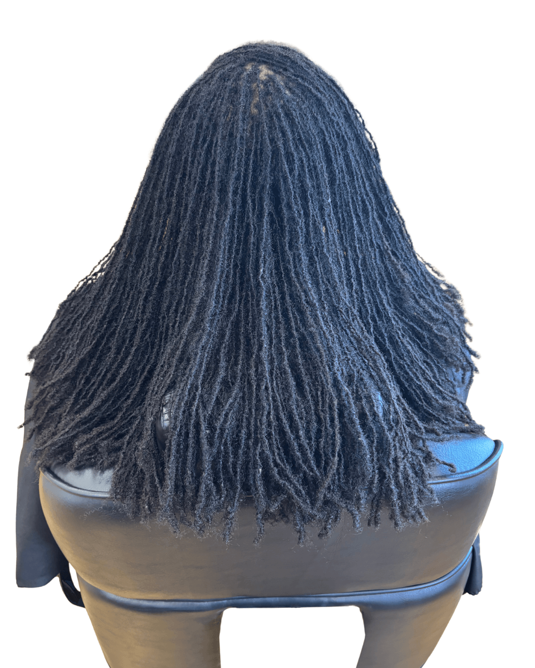 Back view of a person with shoulder-length, textured, dark hair, sitting on a black chair against a white background.